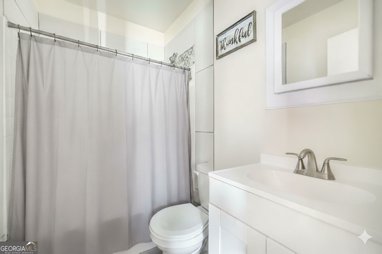 511 Forsyth Street Montezuma, GA 31063 - Photo 10 of 12 a bathroom with a sink a toilet and shower curtain