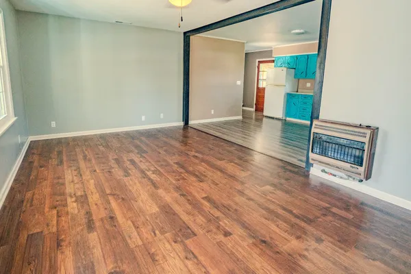 an empty room with wooden floor and mirror