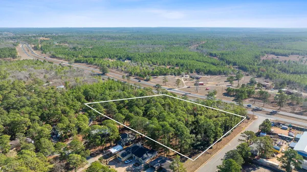 an aerial view of residential houses with outdoor space and trees