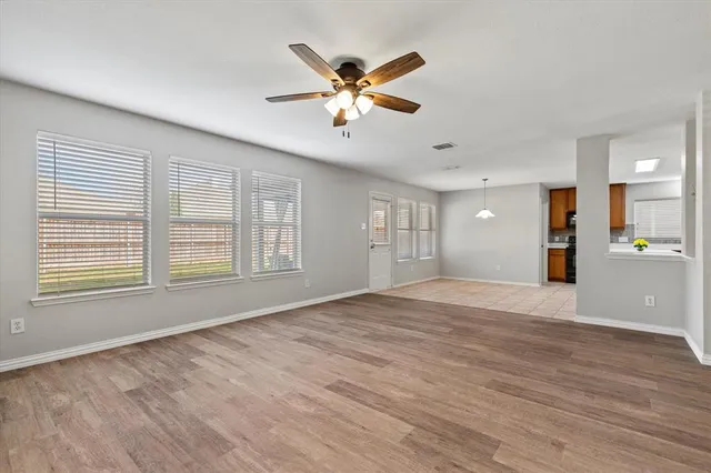 a view of an empty room with window and wooden floor