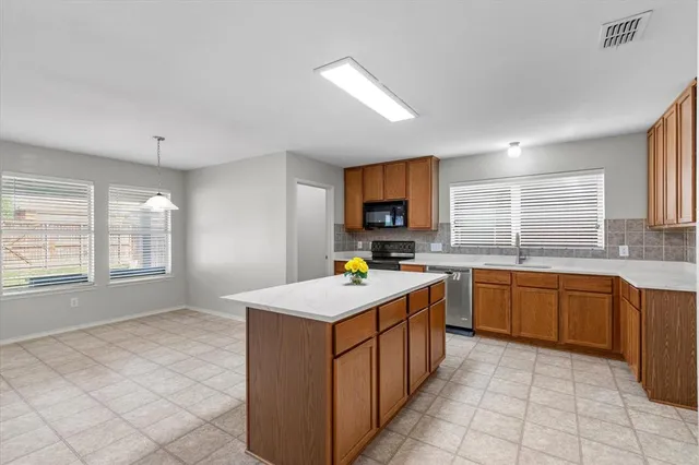 a kitchen with granite countertop a sink a stove top oven a counter space and cabinets