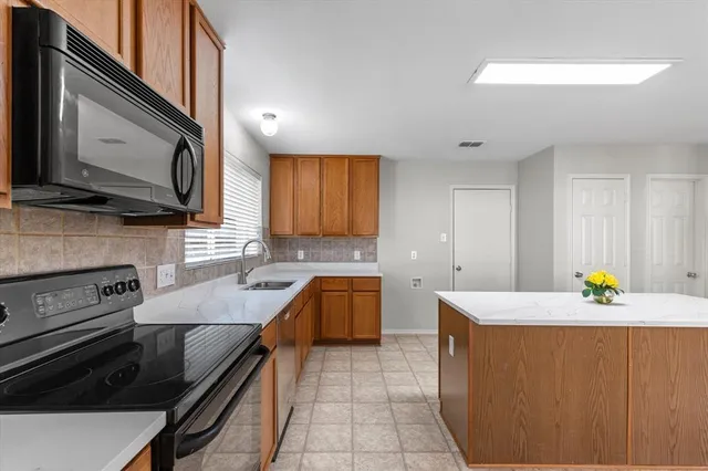 a kitchen with granite countertop a sink a stove top oven and cabinetry