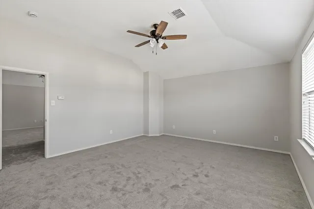 an empty room with a ceiling fan and window