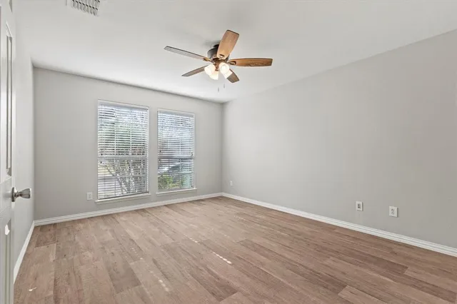 a view of empty room with wooden floor and fan