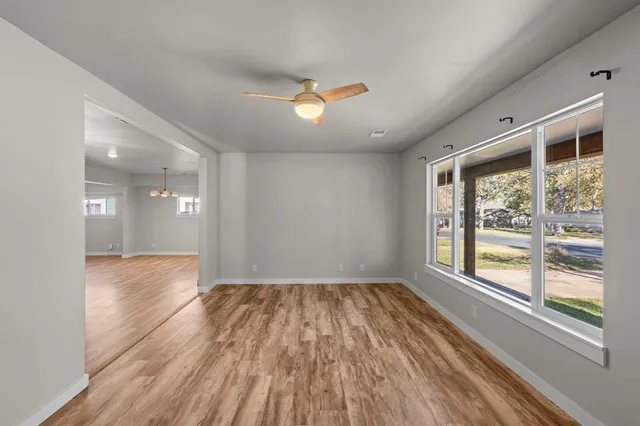 a view of an empty room with wooden floor and a window