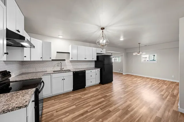 a kitchen with a refrigerator a stove top oven and wooden floor