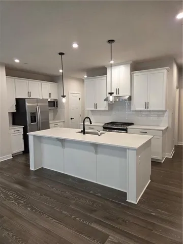 a kitchen with stainless steel appliances kitchen island granite countertop a stove a sink and a refrigerator