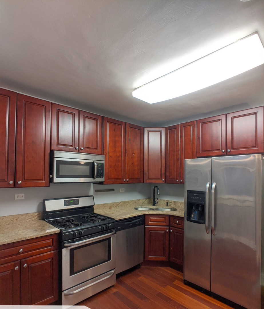 5027 North Harding Avenue, Unit 2W Chicago, IL 60625 - Photo 10 of 20 a kitchen with granite countertop wooden cabinets and stainless steel appliances