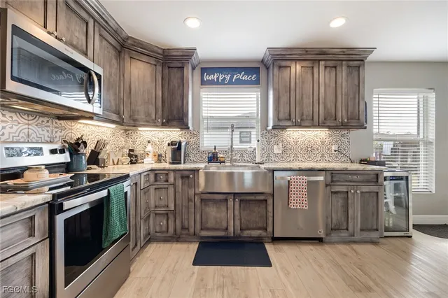 a kitchen with granite countertop a sink cabinets stainless steel appliances and a window