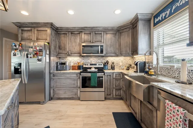 a kitchen with stainless steel appliances granite countertop a refrigerator a sink a stove and cabinets