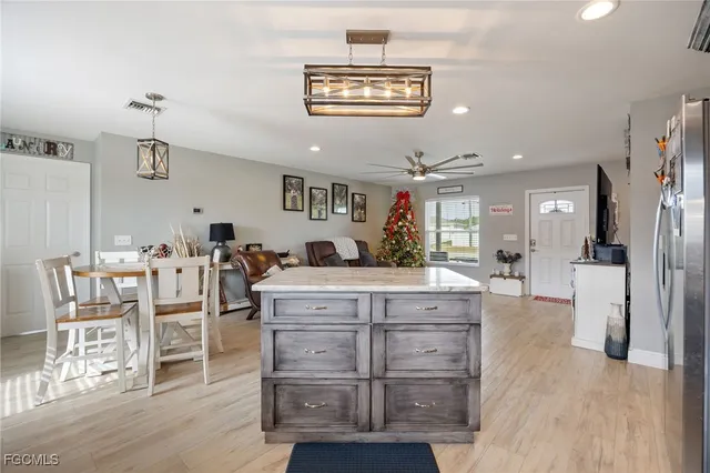 a large kitchen with stainless steel appliances kitchen island granite countertop a refrigerator a stove a dining table and chairs with wooden floor