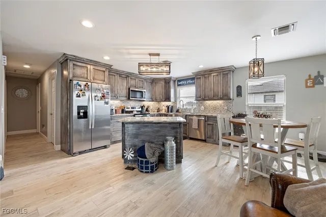 a kitchen with stainless steel appliances a refrigerator a stove a sink and a chairs with wooden floor