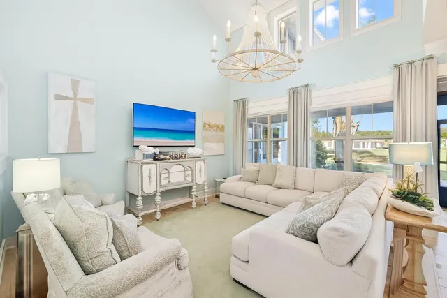 a living room with furniture a chandelier and a large window