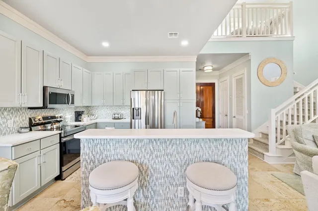 a kitchen with stainless steel appliances a sink a stove a refrigerator cabinets a dining table and chairs