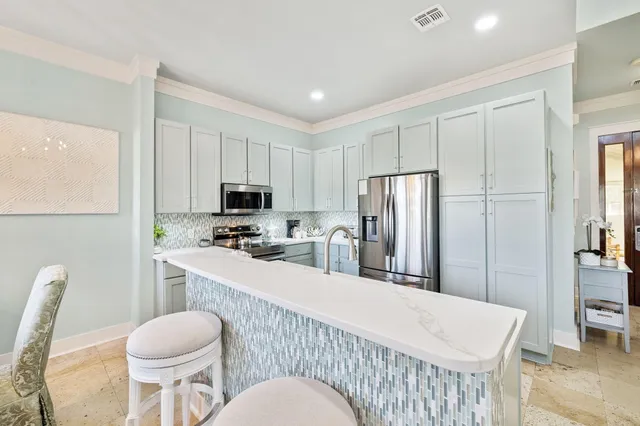 a kitchen with stainless steel appliances a refrigerator a stove a sink a dining table and chairs