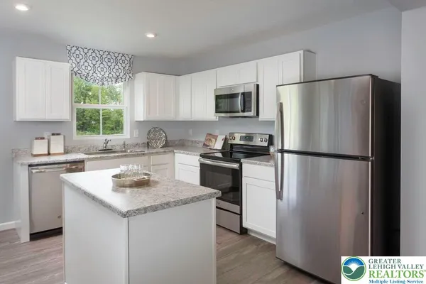 a kitchen with a refrigerator a sink cabinets and wooden floor