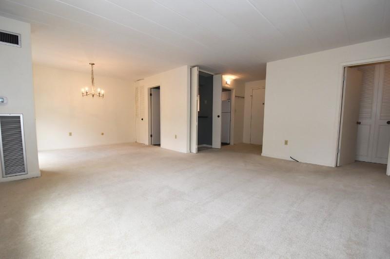 Bright dining/living area with chandelier and generous floor space, offering flexible layout options and convenient access to nearby rooms.