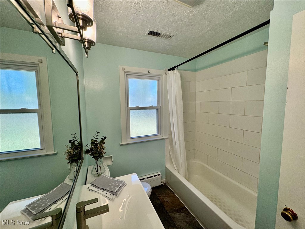 1729 East Pleasant Valley Road Independence, OH 44131 - Photo 26 of 41 Bathroom with toilet, a textured ceiling, baseboard heating, and shower / bathtub combination with curtain