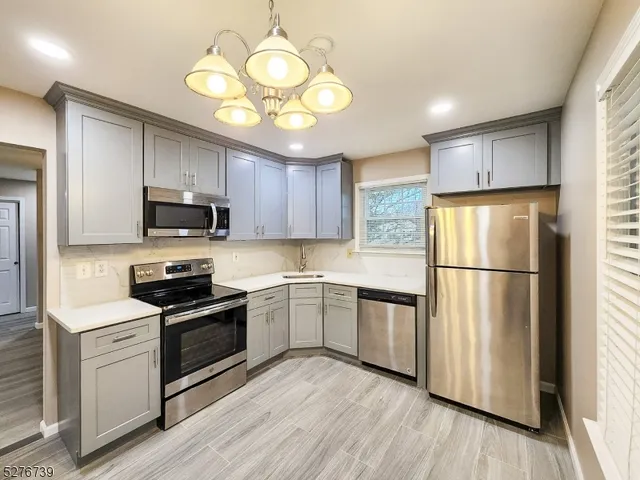 a kitchen with kitchen island granite countertop stainless steel appliances cabinets a sink and a wooden floor