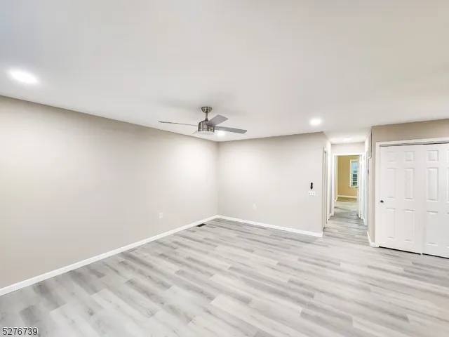 an empty room with wooden floor and ceiling fan