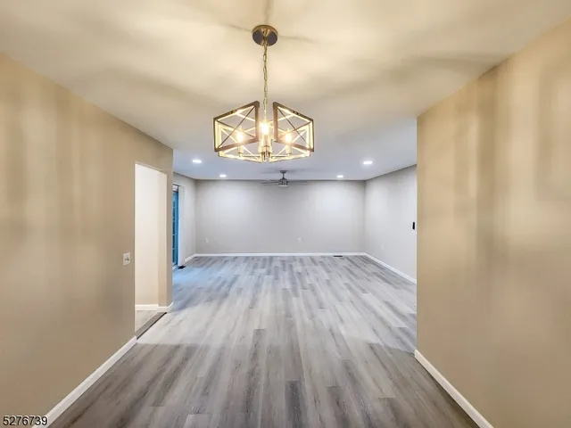 a view of empty room with wooden floor and chandelier