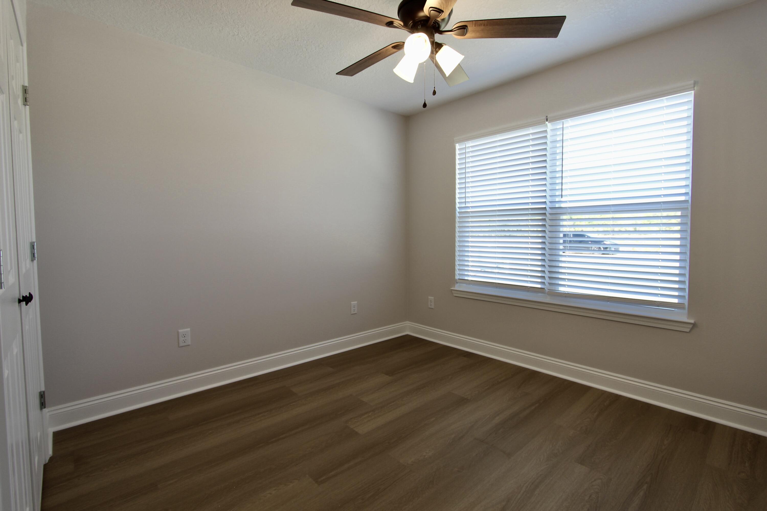 4608 Bobolink Way Crestview, FL 32539 - Photo 14 of 25 a view of an empty room with wooden floor and a window