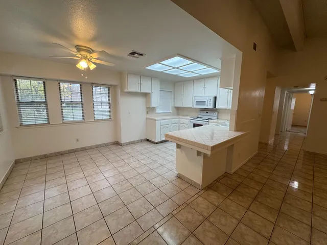 a large white kitchen with kitchen island a sink a counter space and a window