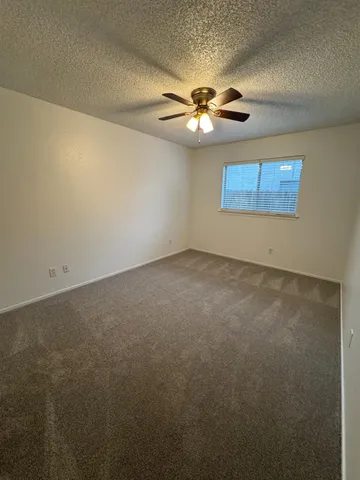 an empty room with a window and a fan