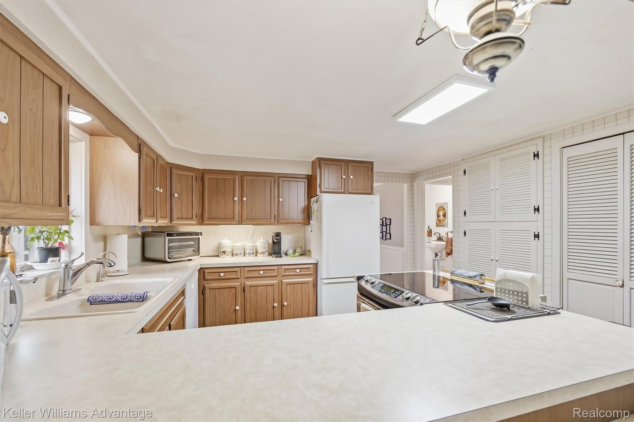 6595 Bray Road Vassar, MI 48768 - Photo 19 of 64 Kitchen featuring light countertops, freestanding refrigerator, wood finish cabinetry, electric range, and a peninsula