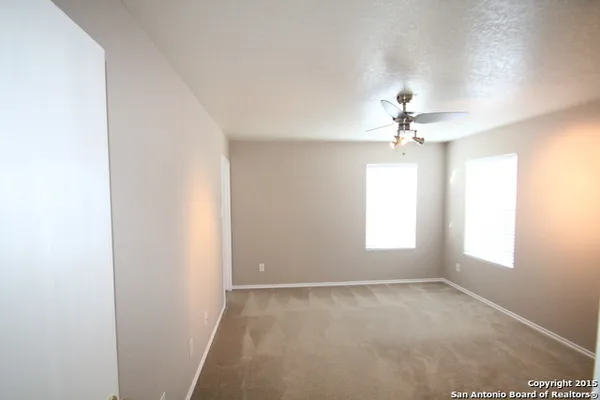 an empty room with windows and chandelier fan