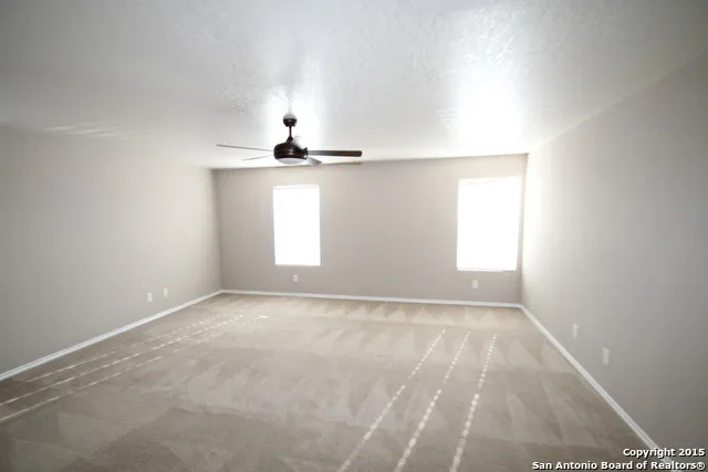 a view of an empty room with chandelier fan