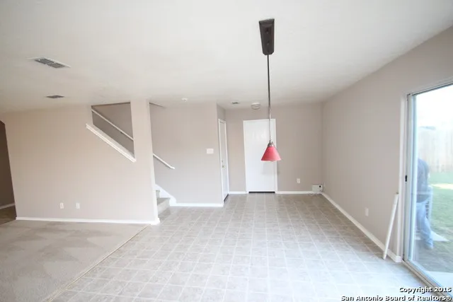 a view of an empty room with cabinet and a chandelier