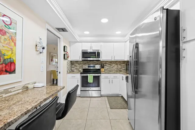 a kitchen with stainless steel appliances granite countertop a refrigerator and a stove top oven