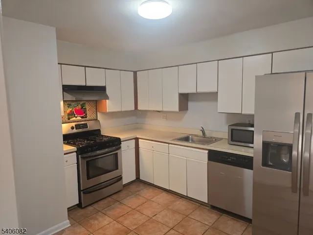 a kitchen with stainless steel appliances granite countertop white cabinets a refrigerator and a stove