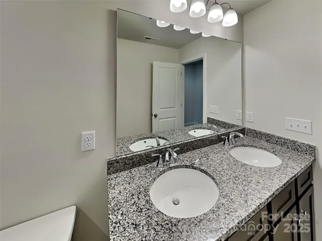 a bathroom with a granite countertop sink a mirror and a toilet