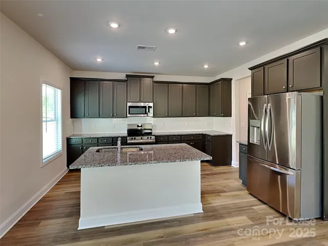 a kitchen with stainless steel appliances granite countertop a refrigerator a sink a stove a microwave and island