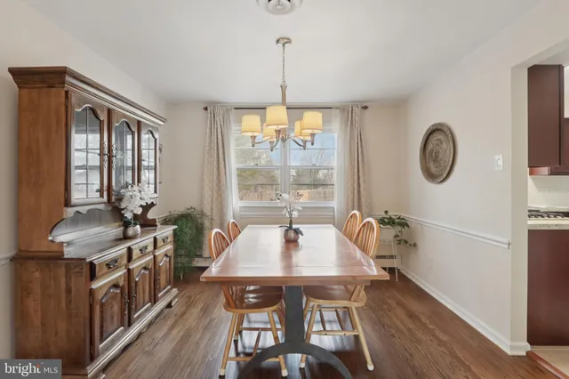 a dining room with wooden floor a chandelier a wooden table and chairs