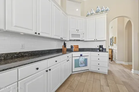 a kitchen with granite countertop white cabinets and stainless steel appliances