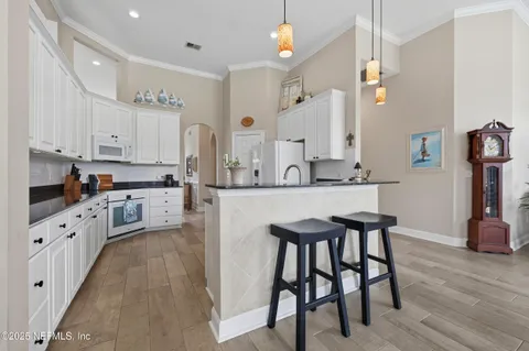 a kitchen with stainless steel appliances kitchen island granite countertop a table chairs sink and cabinets