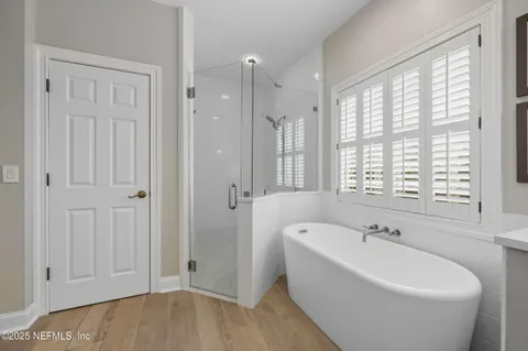 a white bath tub sitting in a spacious bathroom next to a window
