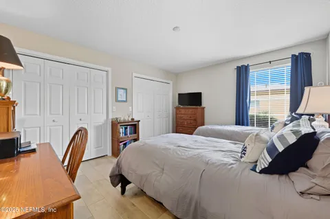 a bedroom with bed a flat tv screen and a dresser