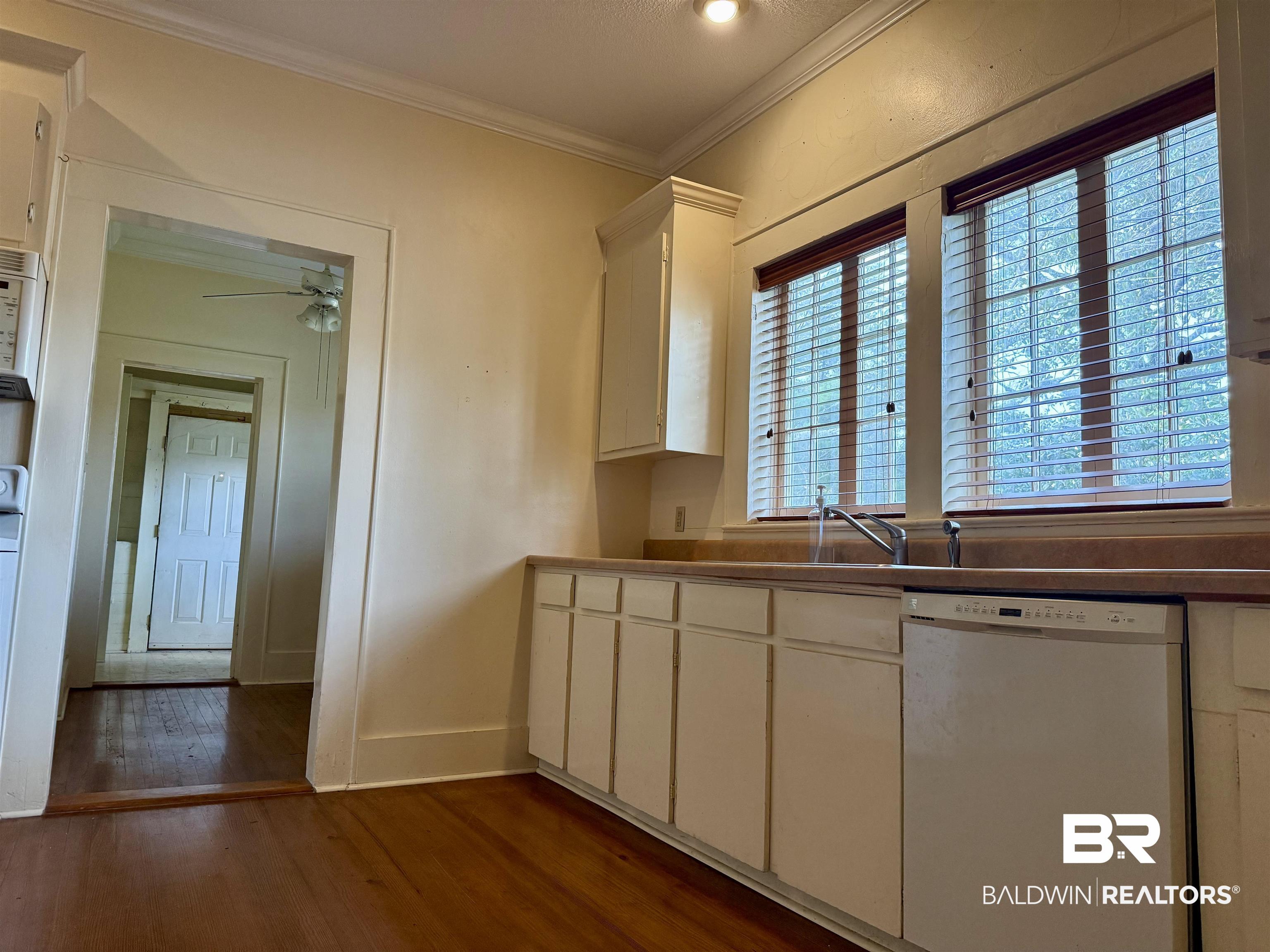 423 Evergreen Avenue Brewton, AL 36426 - Photo 9 of 18 Kitchen with white dishwasher, crown molding, dark wood-style flooring, ceiling fan, and white cabinets