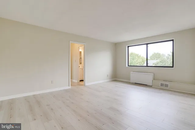 a view of an empty room with a window and wooden floor
