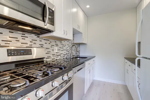 a kitchen with granite countertop white cabinets and a sink