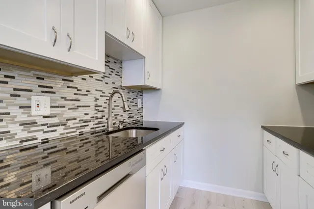 a kitchen with granite countertop white cabinets and a stove