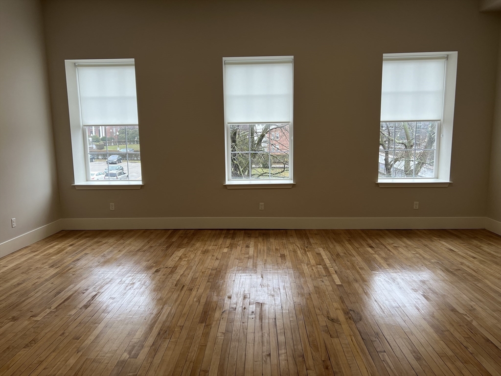a view of an empty room and wooden floor and a window