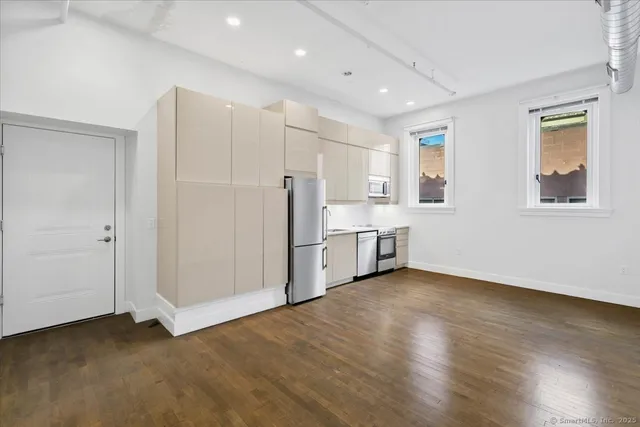 a view of kitchen with stainless steel appliances refrigerator oven and wooden floor