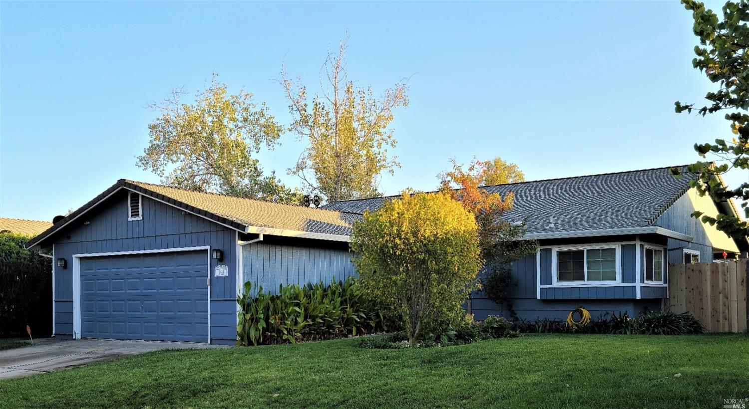 a brick house with a large tree and a yard in front of it