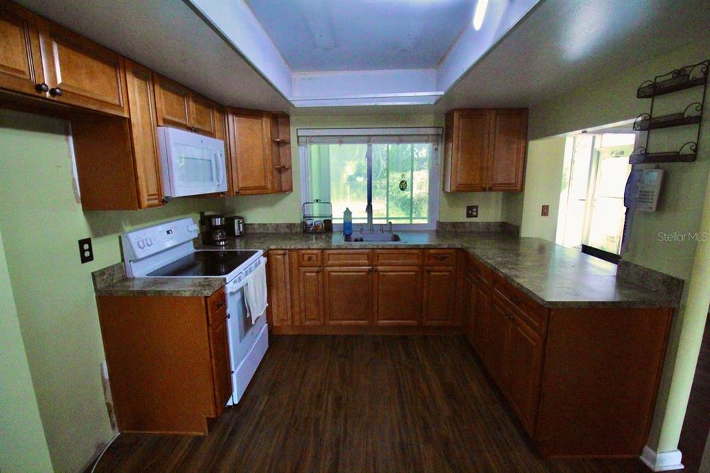 4090 Old Colony Road Mulberry, FL 33860 - Photo 5 of 22 a kitchen with stainless steel appliances a sink dishwasher a refrigerator a stove and wooden cabinets with wooden floor