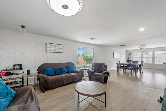 a living room with furniture and a dining table with wooden floor